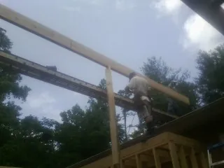 Carpenter setting a ridge beam over a new addition frame — Ice Dam Removal by Roofing Brothers in Ladoga