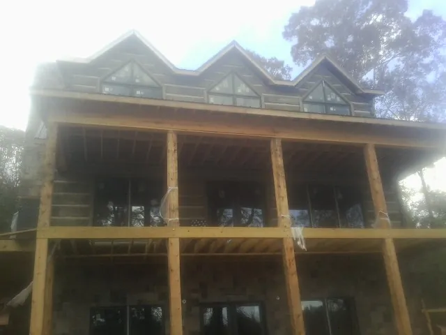 Dormers and porch framing on a large log home under construction — Roof Coating work by our crew in Ladoga
