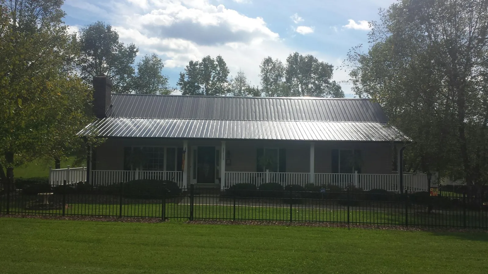 Gray metal roof on a brick ranch with a full width front porch — Gutter Guard Installation work by our crew in Ladoga