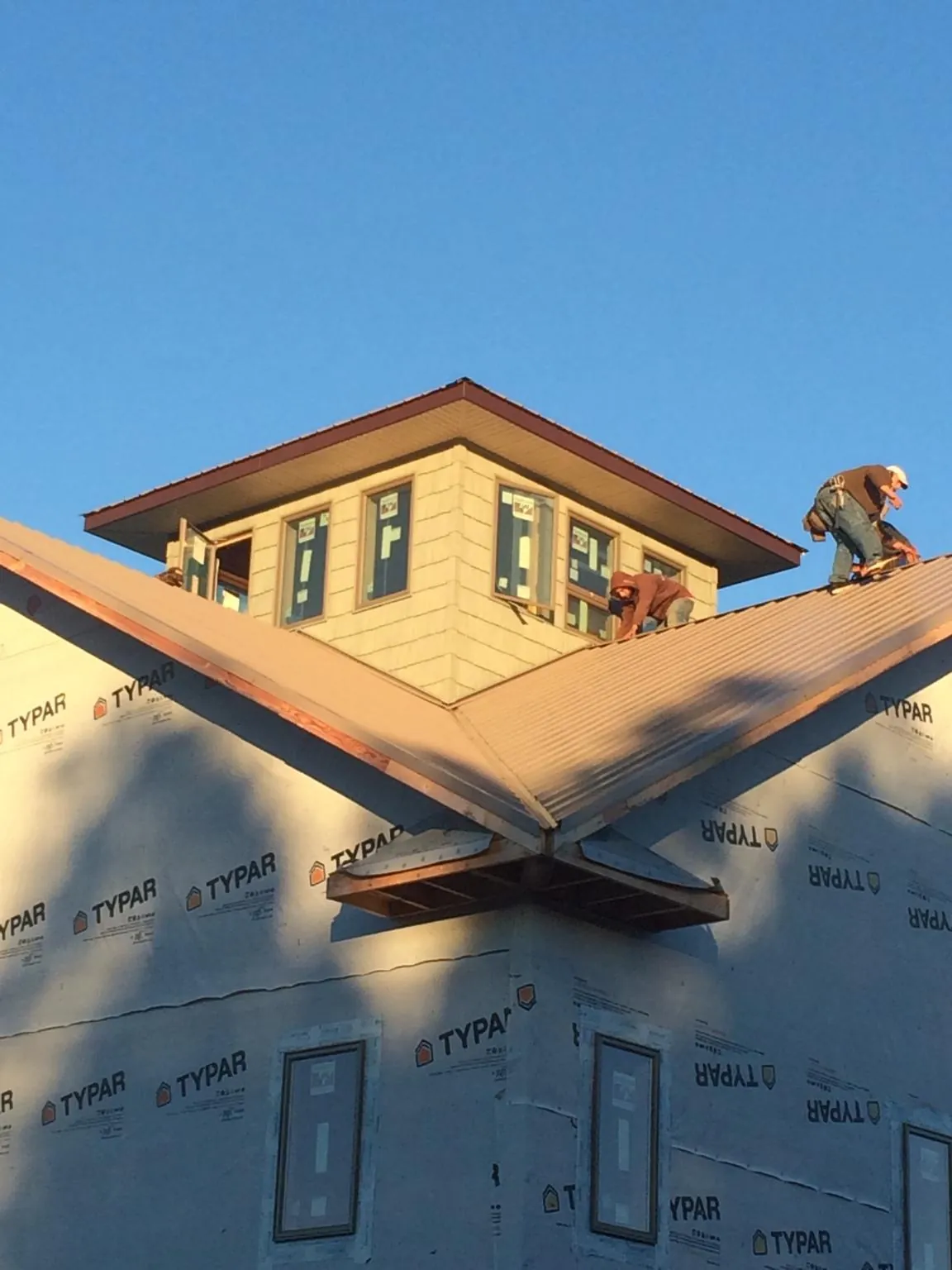 Roofers working around a rooftop cupola on a new metal roof at sunset — Roof Waterproofing in Ladoga by Roofing Brothers